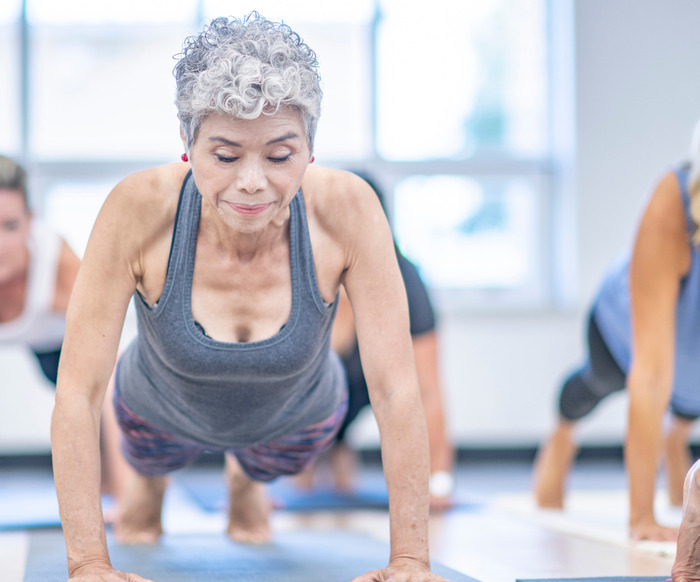 4 Older woman doing a push-up in a group strength class